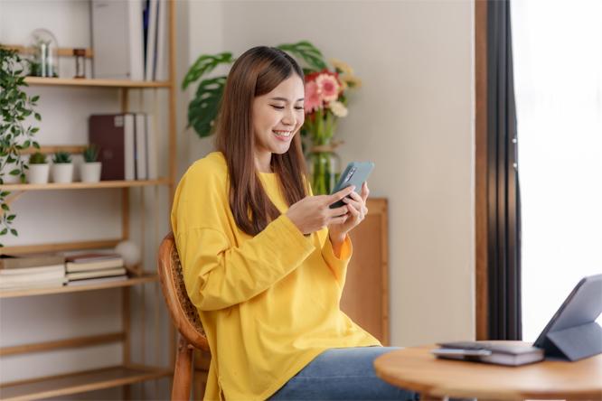 Beautiful young Asian woman using a smartphone transact on social media applications with a smiling face.