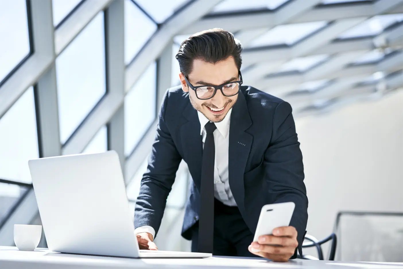 smiling-businessman-looking-at-cell-phone-at-desk